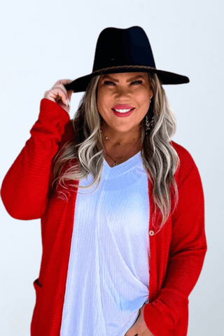 a woman wearing a black hat and a red cardigan