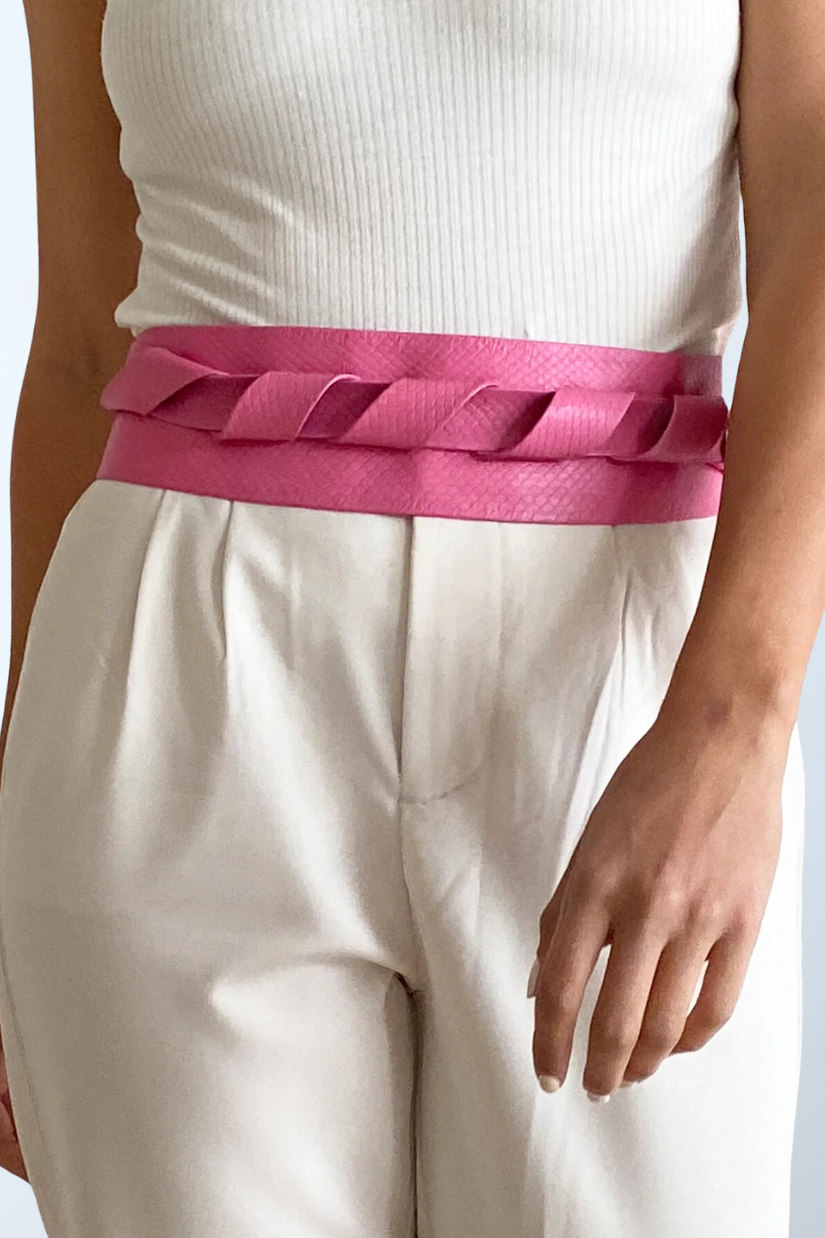 a woman wearing a pink belt and white pants