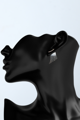 a black mannequin head with a pair of earrings on it