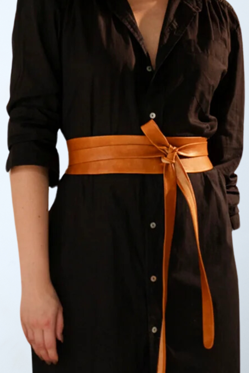a woman wearing a black dress with a brown belt
